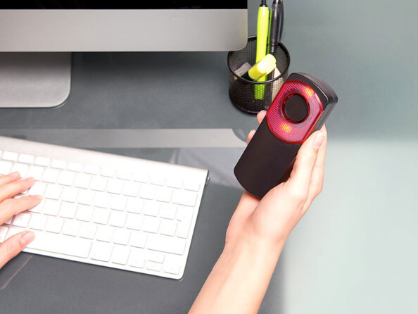 Sonnette tenue en main par une personne devant un ordinateur et tapant sur un clavier