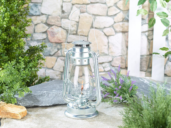 Lanterne à pétrole grise placée devant une habitation en pierre de jour