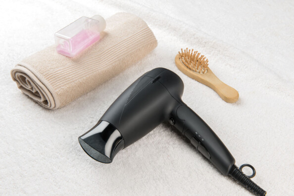 Sèche-cheveux noir mat avec embout concentrateur translucide et poignée à sélecteur 3 positions, vu de côté sur fond blanc