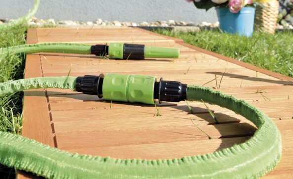 Mise en situation du raccordement de deux tuyaux d'arrosage extensibles verts par coupleur mâle vers mâle