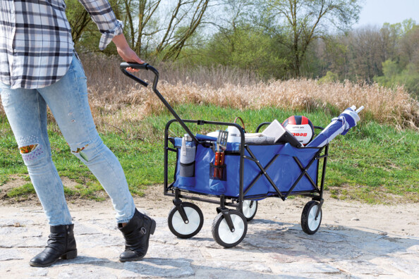 Jeune femme en balade tirant la charette roulante remplie de courses à la main