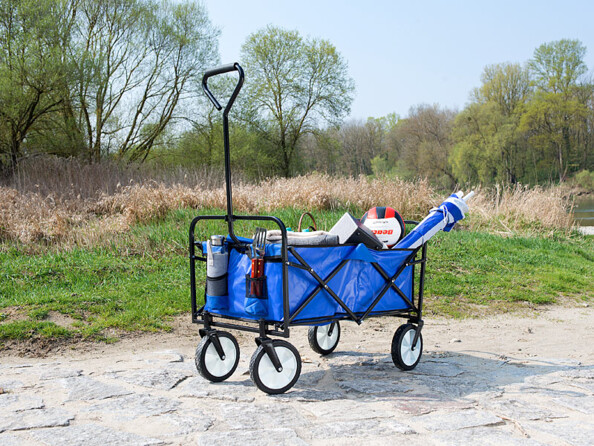 Chariot à roulettes rempli de divers objets sur un chemin de terre dans un parc extérieur