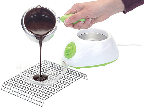 Chocolat fondu dans le récipient en alu avec poignée résistant à la chaleur versé dans un moule en plastique sur une grille en métal