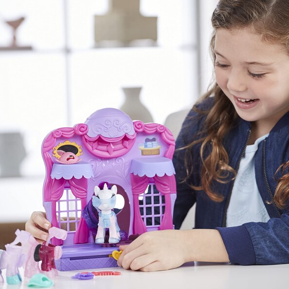 Une petite fille qui s'amuse à faire défiler son cheval dans la Boutique magique My Little Pony.