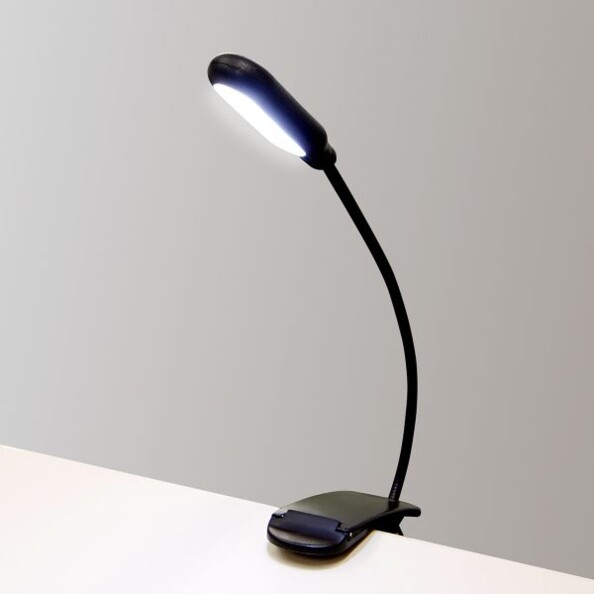 La lampe de lecture à 5 LED McShine, fixée sur le bord d'une table.