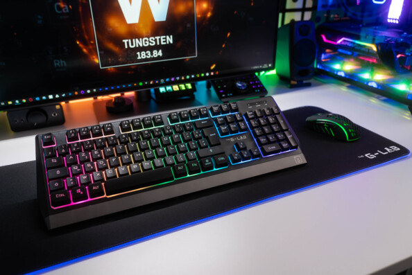 Mise en situation du clavier et de la souris Combo Tungsten de The G-Lab sur tapis de souris et devant un écran d'ordinateur allumé, le tout posé sur un bureau