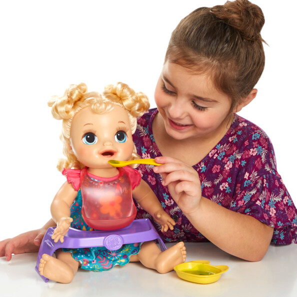 Une petite fille qui nourrit sa poupée "Baby Alive Adore manger".