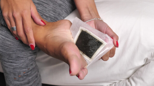 Mannequin aux ongles vernis et à la couleur de peau bronzée retirant le patch collant détoxifiant au bambou après sa sieste d'une seule main