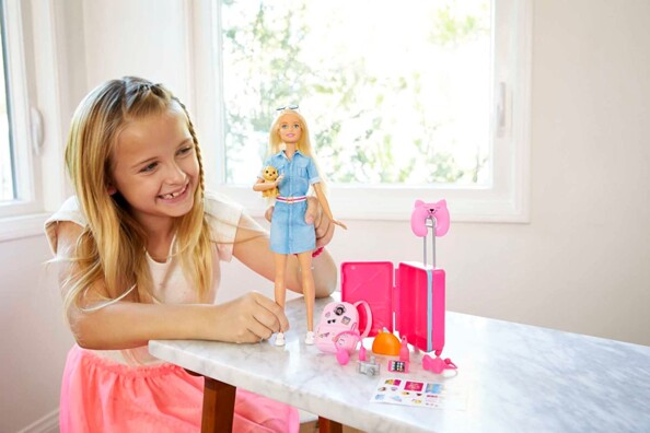 Fille s'amuse avec poupée Barbie voyage et ses accessoires