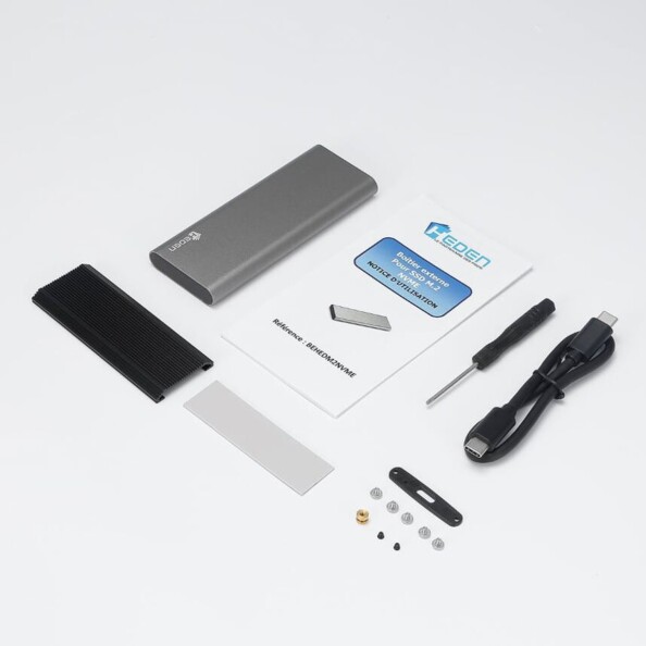 Contenu complet de l'emballage du produit avec mode d'emploi, câble USB-C vers USB-C, tournevis, couvercle thermique en métal, dissipateur en silicone, matériel de montage et boîte en aluminium gris