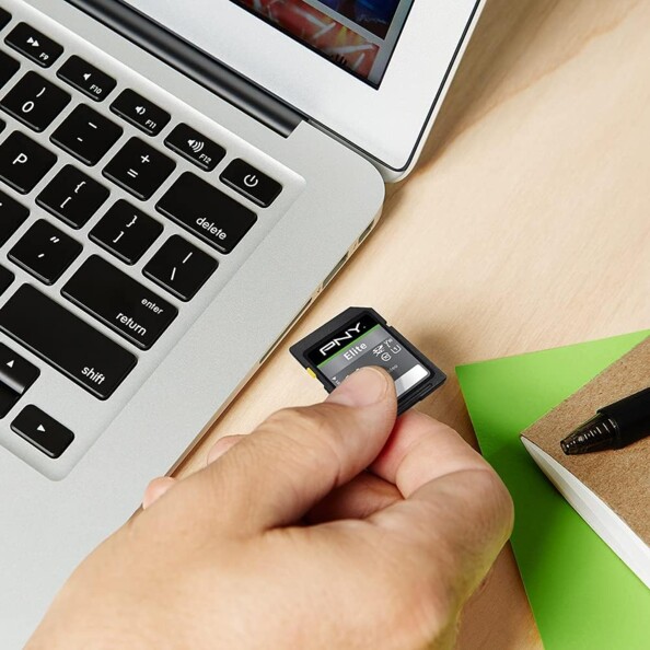 Main insérant une carte SD PNY dans le lecteur de carte mémoire d'un ordinateur portable ouvert