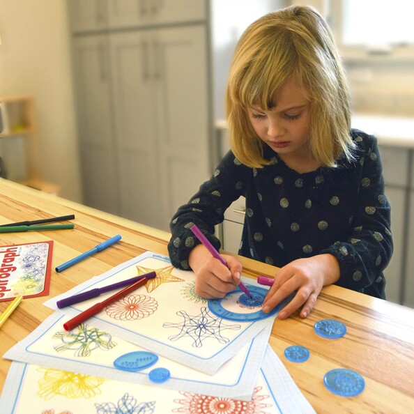 Enfant réalise des dessins et des figures avec Spirograph