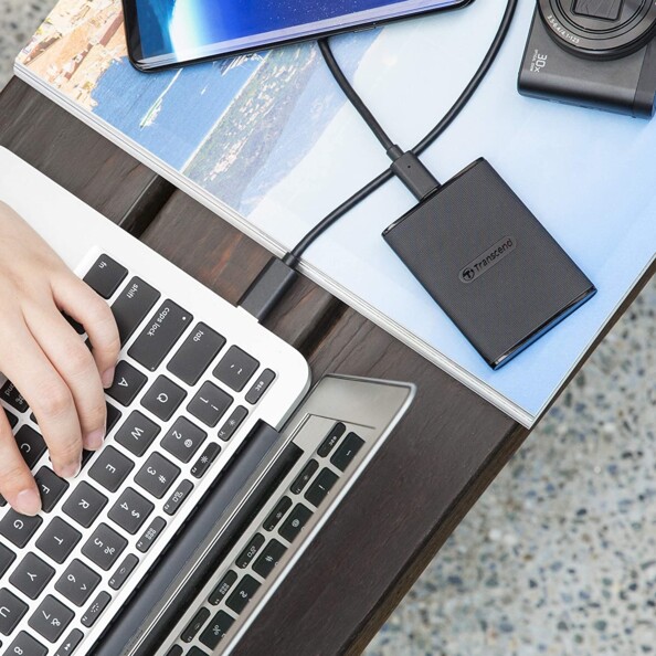 Mise en situation avec ordinateur portable ouvert branché par câble USB fourni au disque dur externe Transcend