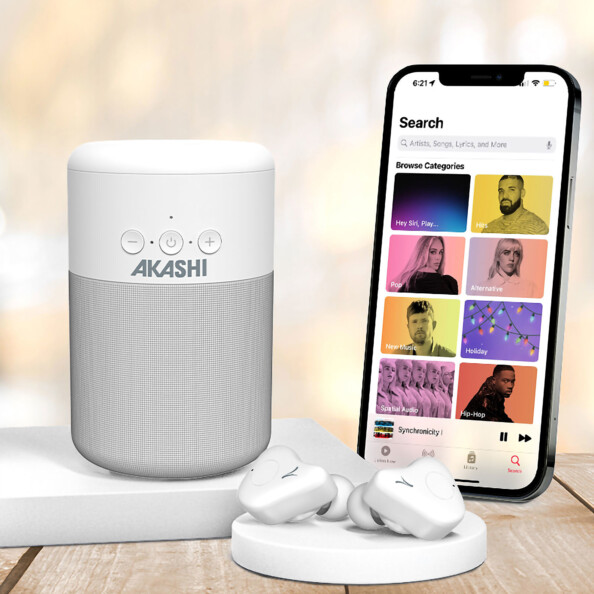 Pack Kanzen avec enceinte et écouteurs sans fil à fonction bluetooth posés à côté d'un smartphone allumée, ouvert sur une application de streaming audio