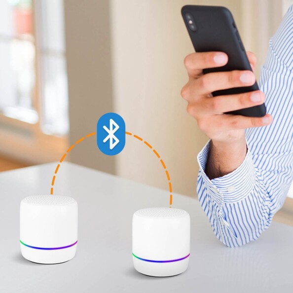 Illustration de la connexion bluetooth entre deux haut-parleurs sans fil avec un smartphone tenue en main par une personne en chemise