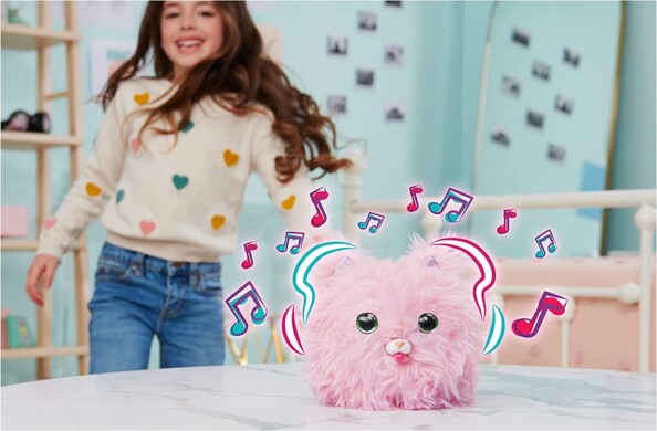 Peluche en fourrure rose dansant et chantant sur une table avec une petit fille dans une chambre d'enfant