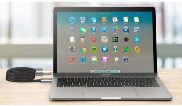 Rallonge USB-C enroulée sur elle-même en étant branchée au port USB-C libre d'un ordinateur portable type Mac allumé sur un bureau en bois clair et à un autre périphérique filaire situé derrière le PC