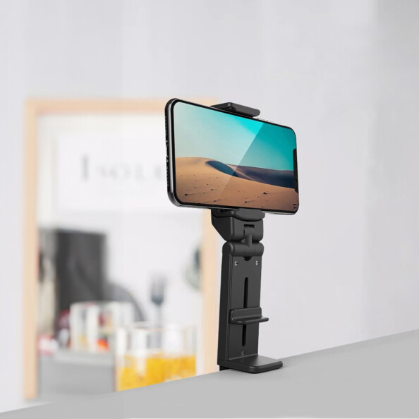 Trépied pour téléphone portable fixé à une table par clip de fixation et à un smartphone allumé positionné à l'horizontale