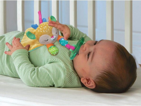 Bébé couché dans son lit avec son doudou Tifan et sa tétine