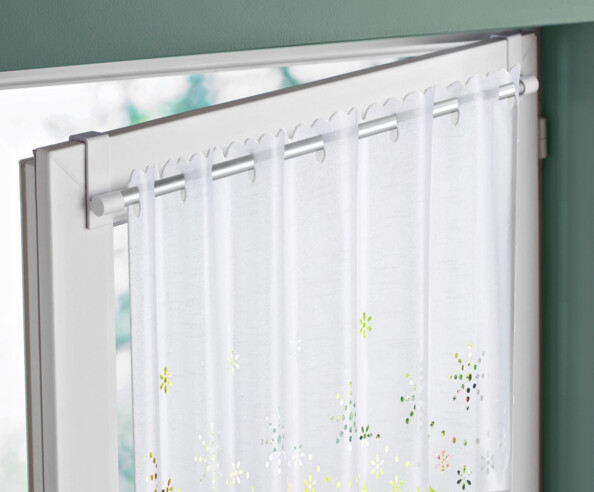 Voile blanc glissé sur la tringle à rideau fixée à une fenêtre