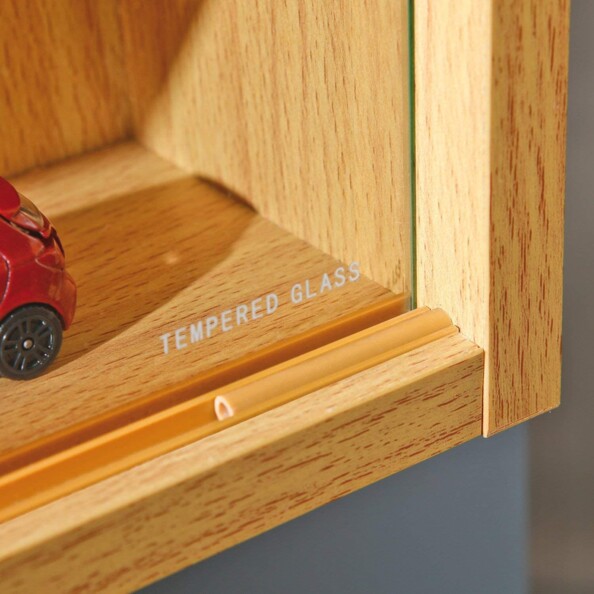 Gros plan sur la mention "Tempered Glass" ou verre trempé sur le coin inférieur droite de la vitre droite de la vitrine avec aperçu du rail coulissant avec système de blocage aspect bois pour ouverture de la vitrine