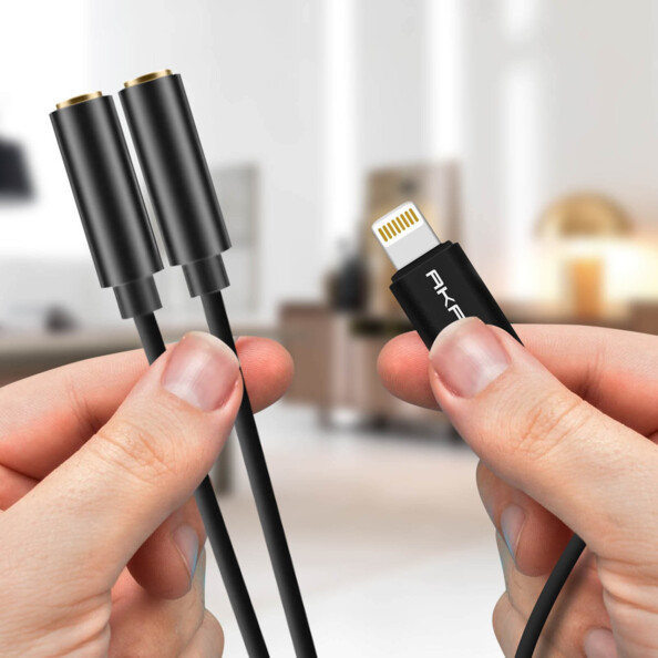 Deux fiches jack 3,5 mm femelles et fiche Lightning mâle tenues entre les deux mains d'une personne