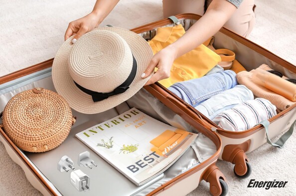 Vue du dessus d'une valise ouverte et en cours de remplissage d'effets personnels dont l'adaptateur secteur de voyage EU/UK/US vers USB 20 W Energizer