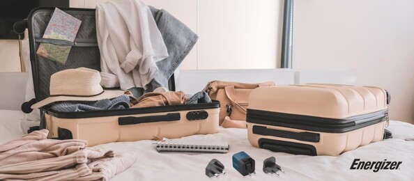 Vue de face de deux valises ouvertes et en cours de remplissage d'effets personnels dont l'adaptateur secteur de voyage EU/UK/US vers USB 20 W Energizer