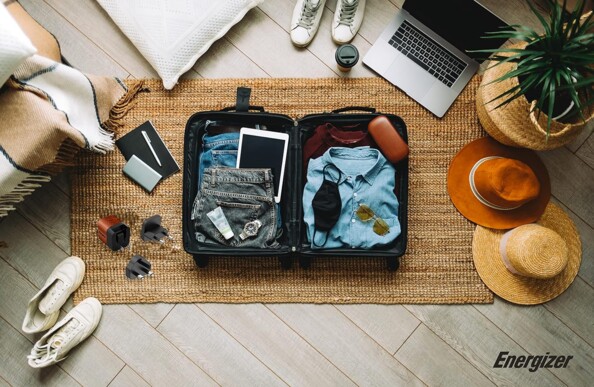 Vue du dessus d'une valise ouverte et en cours de remplissage d'effets personnels dont l'adaptateur secteur de voyage EU/UK/US vers USB 20 W Energizer