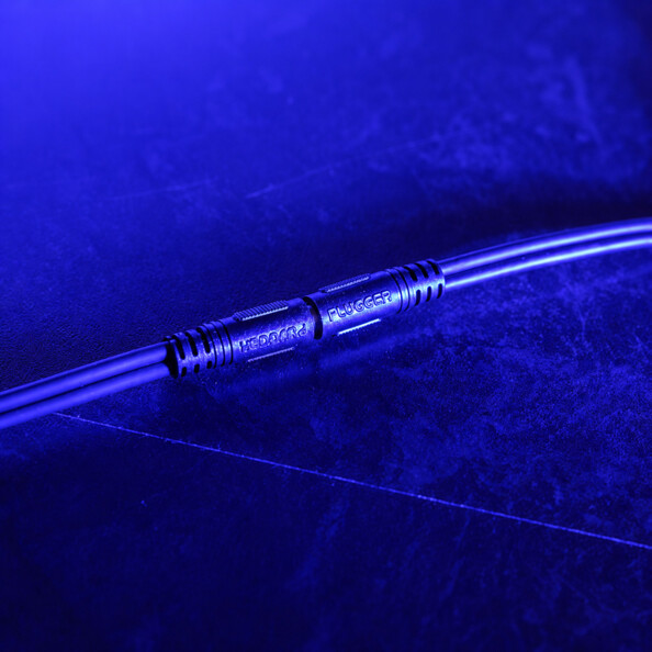 Câbles audio PLUGGER parallèles avec connecteurs métalliques striés sous éclairage bleu