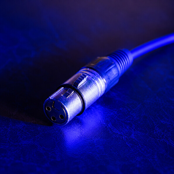 Gros plan d’un connecteur XLR femelle à trois broches dorées sur fond bleu