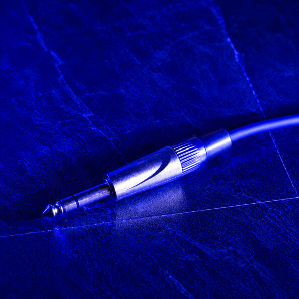 Gros plan d’un connecteur jack TRS 6,35 mm chromé sur surface texturée bleue