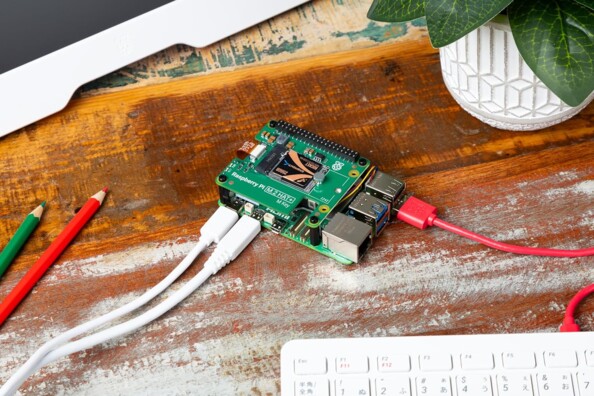 Mise en situation de la carte M.2 HAT+ avec disque dur interne SSD PCIe NVMe installée sur le circuit imprimé d'un nano-ordinateur Raspberry Pi 5 branché à un périphérique USB et à l'alimentation par le biais de câble disposés sur un établi