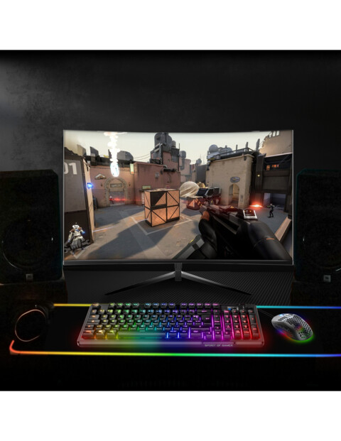 Mise en situation du clavier lumineux dans un setup gaming plongé dans le noir avec écran PC, tapis de souris et souris sans fil