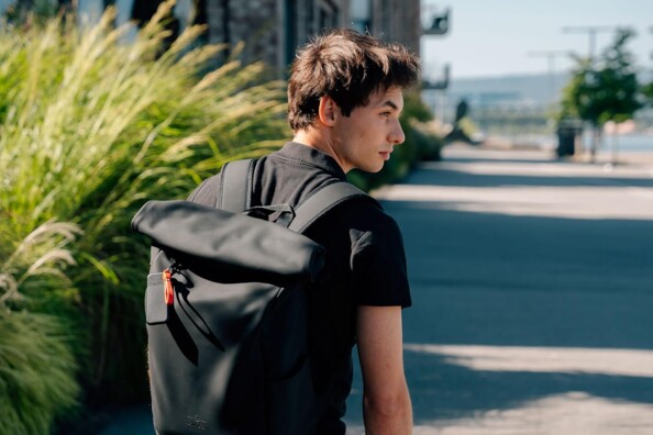 Disque dur SSD Pocket Verbatim accroché à la tirette d'un sac à dos porté par un jeune homme marchant dans la rue