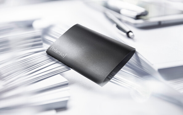 Mise en situation du disque externe SSD noir entre des feuilles de papier blanches