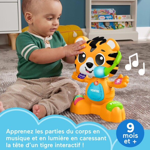 Apprentissage des parties du corps par uné bébé assis à côté du jouet tigre interactif dont il bouge la tête dans une salle de jeu