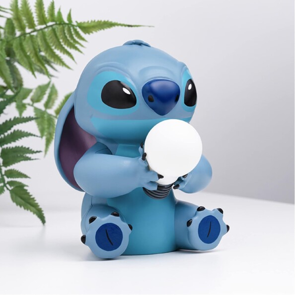 Figurine lumineuse Stitch assis avec ampoule dans les mains à côté d'une fougère