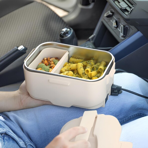 Mise en situation de la boîte repas en plastique et inox coloris crème dans une voiture sur les genoux d'une personne
