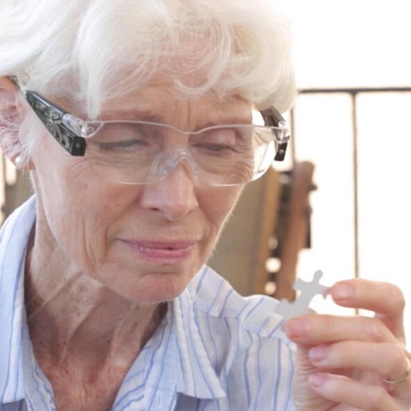 Grand-mère analysant une pièce de puzzle tenue en main avec les lunettes de vue grossissantes à LED Zoom Vision +