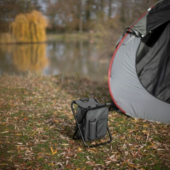 Siège de camping et sac à dos de transport déplié et posé dans la nature à côté d'une tente montée