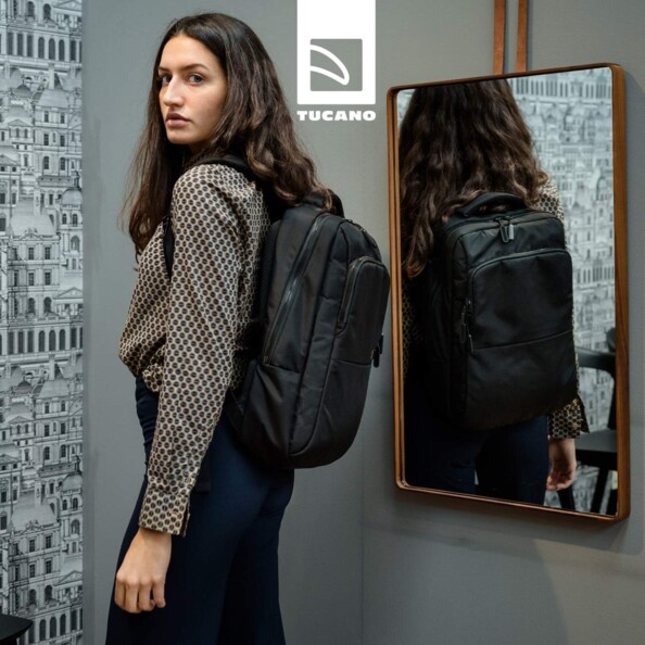 Jeune femme portant le sac à dos Luna Gravity noir sur ses épaules devant un miroir en étant de biais côté gauche