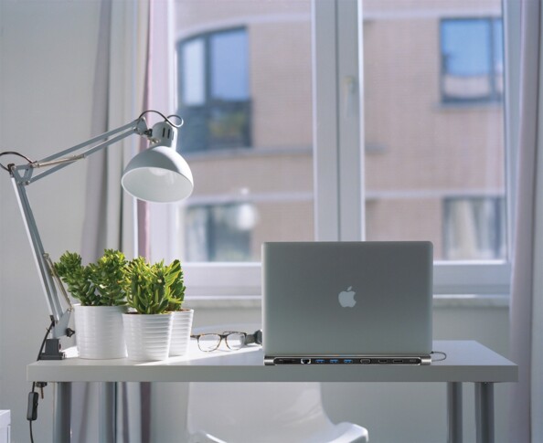Espace de travail lumineux avec MacBook sur dock USB-C devant une fenêtre avec plantes