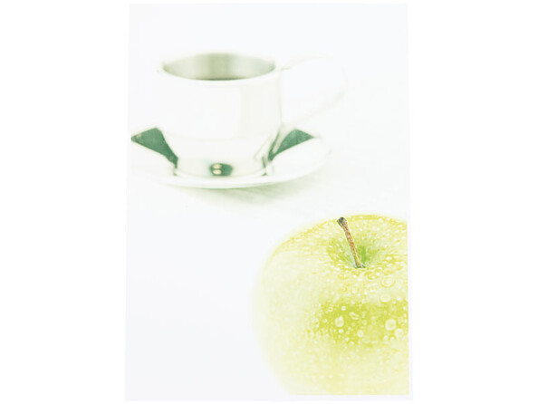Photo en mode Portrait d'une tasse à café blanche sur une soucoupe bicolore avec une pomme type granny smith perlée au premier plan