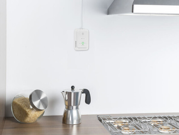 détecteur de gaz domestique connecté mis en situation sur un mur de cuisine au dessu d'une gazinière