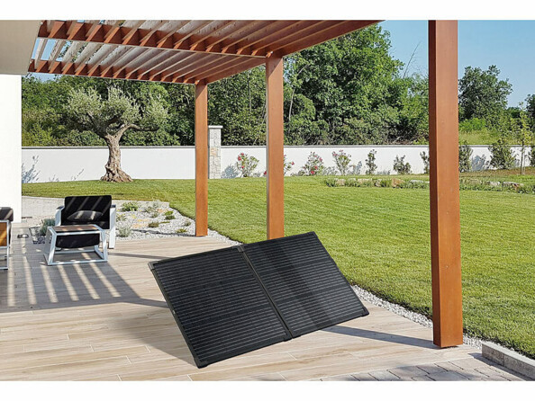 Panneau solaire compatible utilisation marine posé sur une terrasse en bois sous une pergola en bois en extérieur dans un jardin face au soleil