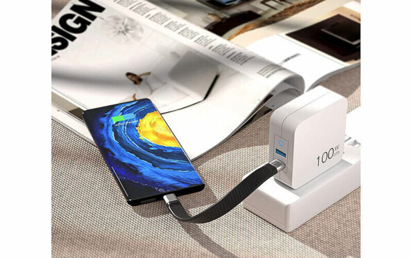 Smartphone Android en cours de chargement posé sur un magazine par le biais du câble tressé USB-C vers USB-C branché à un adaptateur secteur USB raccordé à une station d'accueil secteur