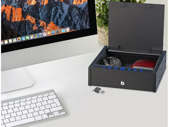 Effets personnels sécurisés dans le coffre-fort connecté ouvert situé à côté d'un Mac sur un bureau