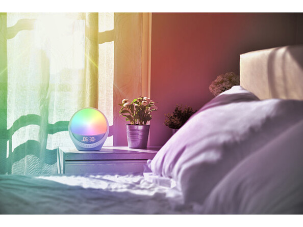 réveil simulateur d'aube lever de soleil connecté mis en situation sur un chevet avec lumière RGB