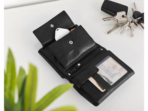 Porte-clés siffleur rangé dans un portefeuille noir déplié à côté d'un trousseau de clés